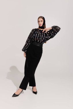 Genç bayan zarif bir şekilde poz veriyor, şık stilini ve özgüvenini vurguluyor..