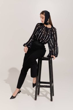 Güzel genç bir kadın zarif bir şekilde poz verir, tarzını vurgular..