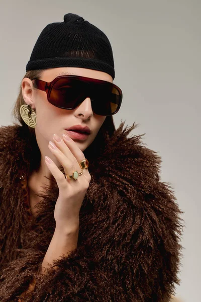 Modaya uygun genç bir kadın, zarif bir şekilde süslenip püslenirken sahte kürk bir ceketle rahatça poz verir..