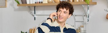 Yakışıklı genç bir adam animasyonlu bir telefon görüşmesi yapıyor, şık bir mutfakta sıcaklık yayıyor..