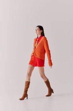 Walking gracefully, a beautiful young woman showcases her unique style in striking colors.