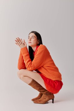 Beautiful woman showcases her fashion sense in a playful crouch, exuding style and elegance.