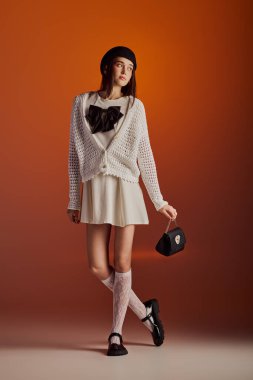 Beautiful young woman poses fashionably against a striking warm background, radiating confidence.