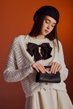 Genç bir kadın şık bir süveter ve çarpıcı yay aksesuarlarıyla moda anlayışını sergiliyor..