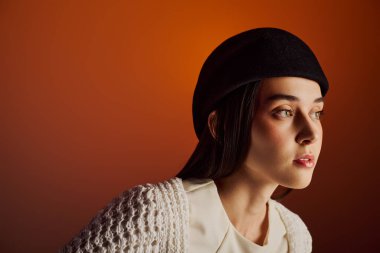 Tarz sahibi genç bir kadın, şık kıyafetlerini sıcak bir ortamda sergiliyor..