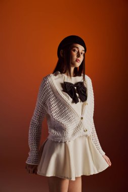 Genç bir kadın, şık beyaz bir hırka ve hoş bir etek giyiyor..