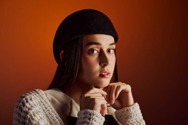 Uzun saçlı, modaya uygun bir şapka takan şık bir kadın eşsiz güzelliğini ön plana çıkarıyor..