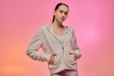 Moda kıyafetleri içinde şık bir genç kadın renkli bir arkaplana karşı güven yayıyor..