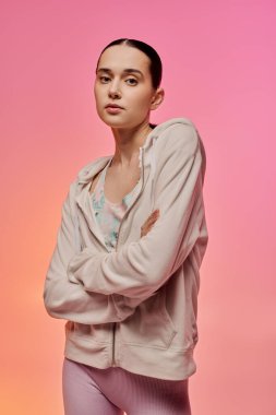 Şık, genç bir kadın kollarını kavuşturup, hareketli bir arkaplanda poz veriyor..