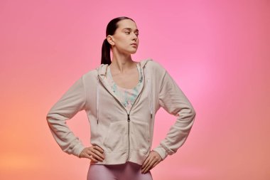 Genç bir kadın, modaya uygun pastel kıyafetiyle gösteriş yaparak kendine güvenen bir poz verir..