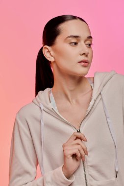 Genç bir kadın modaya uygun tarzını rahat bir kapüşonluyla sergiliyor, zarafet ve duruş yayıyor..