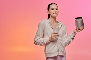 Güzel bir kadın, rahat bir ortamda güven içinde poz verirken bir konteynır ve titretici tutuyor..