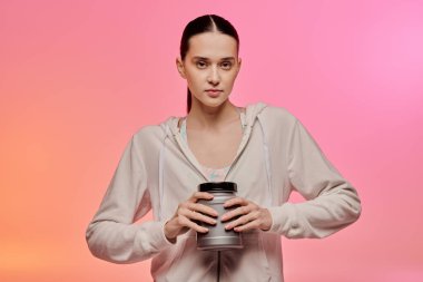 Modaya uygun bir kadın kendine güvenerek renkli bir ortamda parlak bir konteynırı sallıyor..