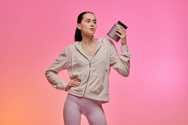 Şık giyinmiş genç bir kadın bir konteynır taşıyor, özgüven ve benzersiz moda anlayışı gösteriyor..