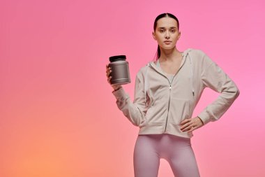 Kendine güvenen bir kadın canlı bir arka plana karşı zindelik takviyesi sergiliyor..