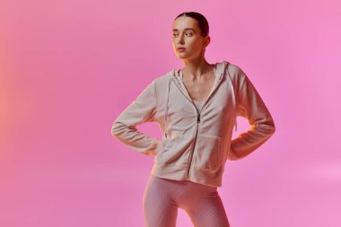 Şık bir kadın, rahat bir şekilde pembe bir arka plana karşı poz verir..