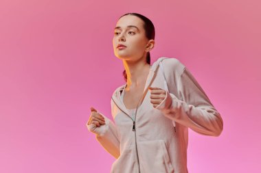 Moda kadını, yumuşak pembe renklerle dolu neşeli bir atmosferde neşeyle dans eder..