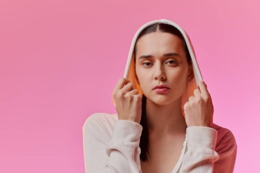 Kapüşonlu şık bir kadın parlak renklerin arasında cesur bir görünüm sergiliyor..