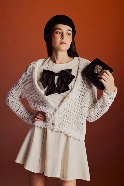 Genç bir kadın, çağdaş ve klasiği birleştiren şık bir elbiseyle rahatça poz verir..