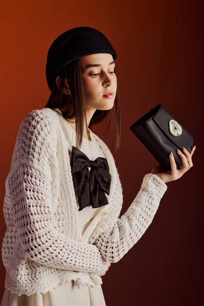 Zarif genç bir kadın şık bir siyah debriyaj ile poz veriyor..