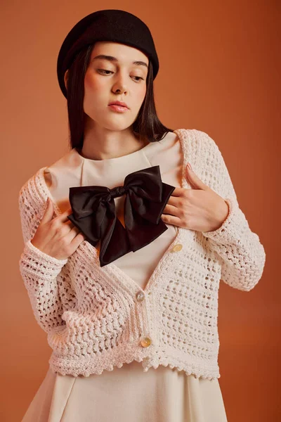 Güzel bir kadın şık bir elbise giyer. Şık bir hırka ve sembolik bir fiyonk giyer. Zarifçe poz verir..