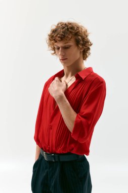 Kıvırcık saçlı genç bir adam canlı kırmızı bir gömlek içinde, zarafet saçıyor..