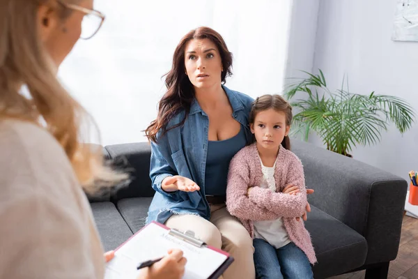 Madre preocupada abrazando a su hija mientras visita al psicólogo - foto de stock