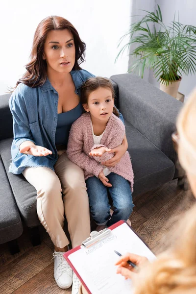 Madre preocupada abrazando a su hija mientras visita al psicólogo - foto de stock