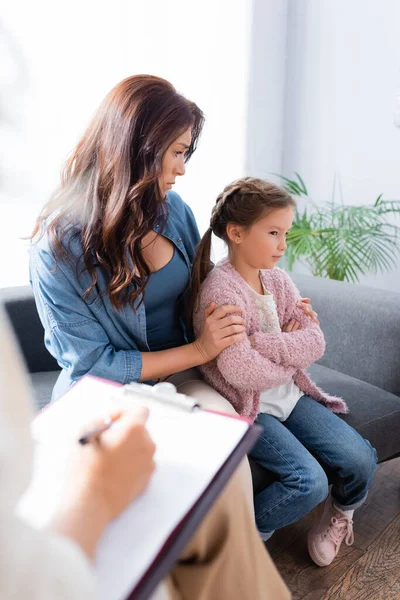 Worried mother hugging daughter while visiting psychologist — Stock Photo