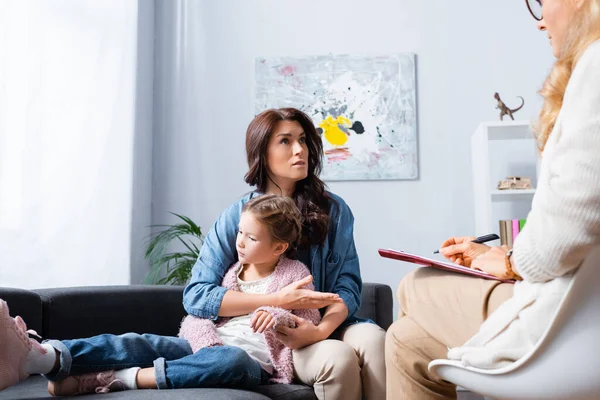 Worried mother hugging daughter while visiting psychologist — Stock Photo