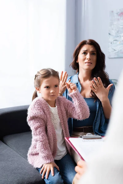 Mère inquiète et fille en colère avec poing serré psychologue visiteur — Stock Photo