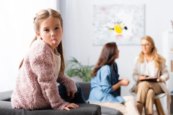 Hija tonteando mientras madre hablando con psicólogo - foto de stock