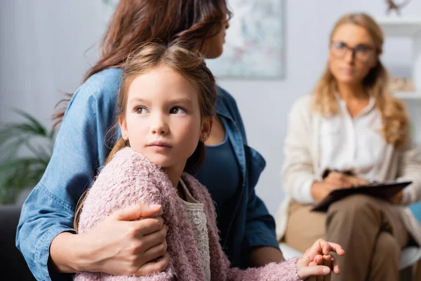 Recortado vista de madre abrazando hija mientras visita psicólogo — Stock Photo