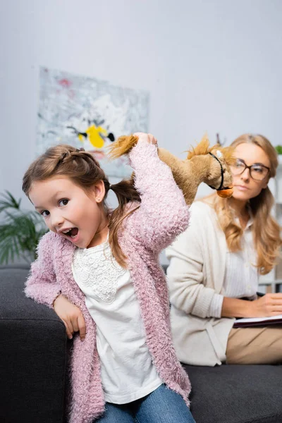 Розлючена дівчинка кидає іграшку під час відвідування психолога — стокове фото