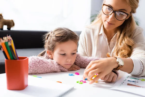 Paciente niña calculando con cifras mientras visita a psicólogo - foto de stock