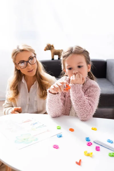 Paciente niña calculando con cifras mientras visita a psicólogo - foto de stock