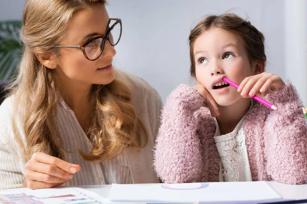 Little girl drawing pictures with colorful pencils while visiting psychologist — Stock Photo