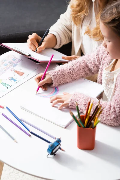 Kleines Mädchen zeichnet beim Psychologen-Besuch Bilder mit Buntstiften — Stockfoto