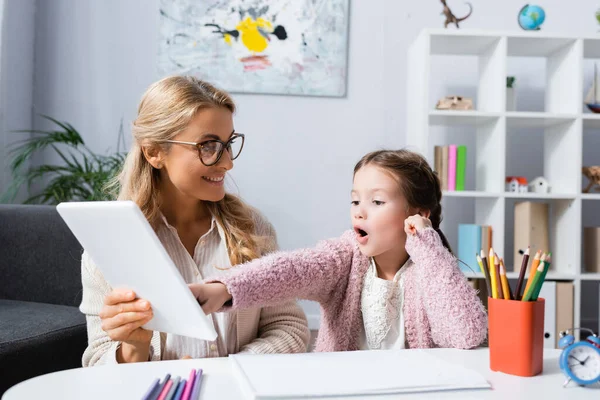 Aufgeregtes Kind zeigt beim Psychologen-Besuch auf digitales Tablet — Stockfoto
