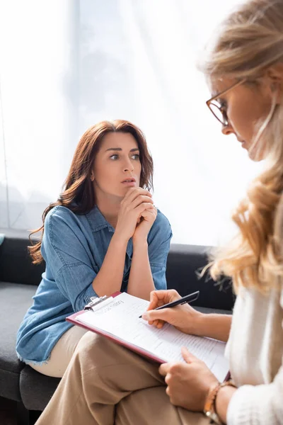 Verängstigte brünette Frau mit psychischen Problemen besucht Therapeuten — Stockfoto