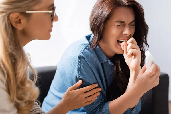 Brünette Frau beißt in Finger, während Therapeut Patientin beruhigt — Stockfoto