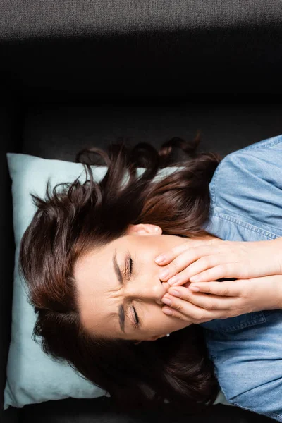 Top view of brunette woman crying and covering mouth — Stock Photo