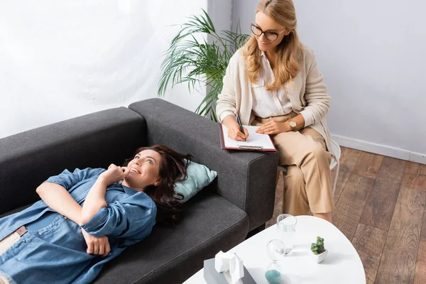 Felice donna bruna sdraiata sul divano durante la visita terapeuta — Foto stock