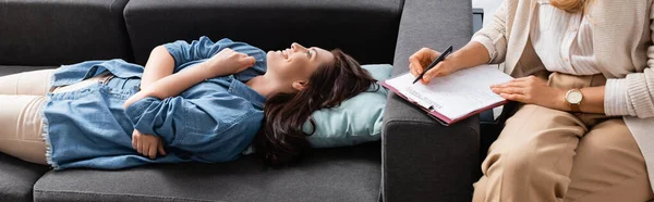 Femme brune heureuse allongée sur le canapé tout en visitant thérapeute, bannière — Photo de stock