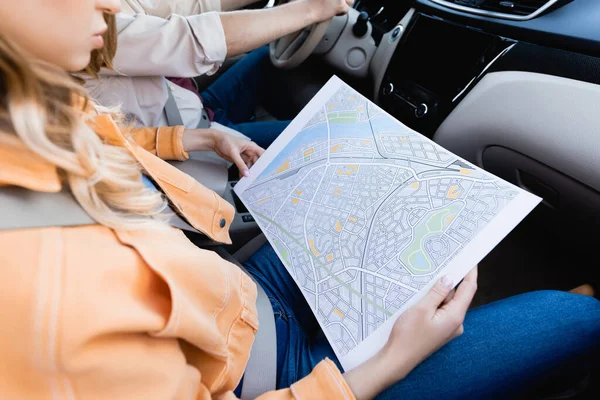 Vista cortada da mulher segurando mapa perto do marido dirigindo carro no fundo embaçado — Fotografia de Stock