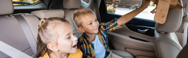 Cheerful siblings with toy plane sitting in auto, banner — Stock Photo