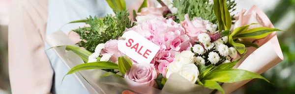 Vista cortada de florista segurando buquê com venda lettering na tag, banner — Fotografia de Stock