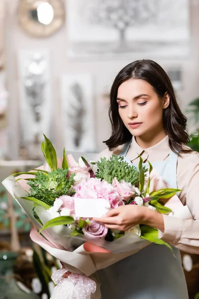 Молодий флорист кладе порожню мітку на святковий букет у квітковому магазині — стокове фото