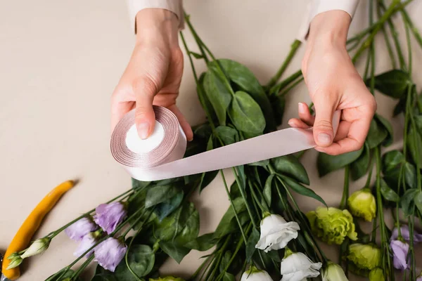 Vista superior do florista segurando fita decorativa enquanto organiza buquê com flores de eustoma — Fotografia de Stock