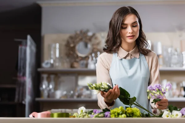 Jovem florista arranjar buquê com flores eustoma na loja de flores no fundo borrado — Fotografia de Stock